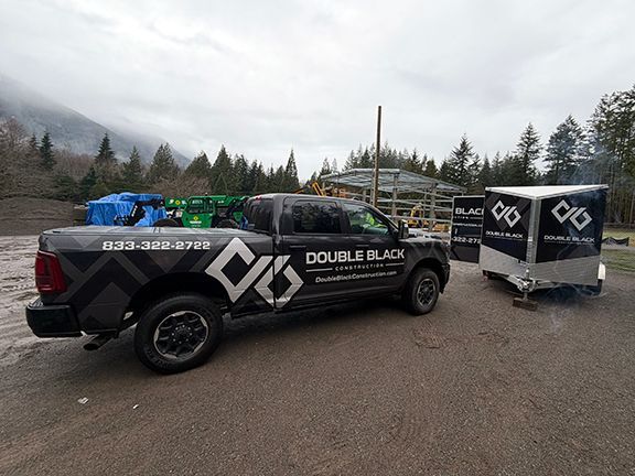 A gray pickup truck with Double Black Construction branding parked outdoors next to a matching trailer in Squamish, BC.