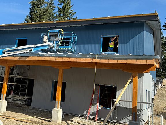 Crane helps lower metal roof panels to building overhang at BC job site.