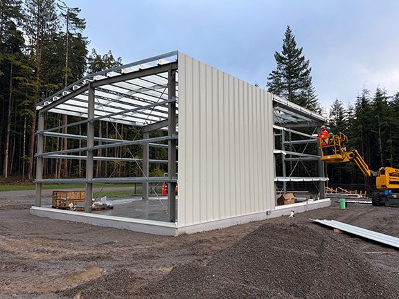 Metal siding panels being added to building frame.