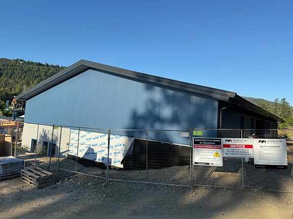 View shows how metal building is being installed against hilly B.C. terrain.