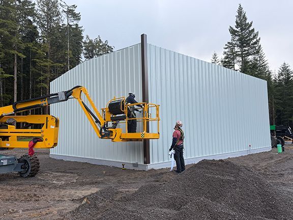 Tradespeople complete wall panels for metal building project.