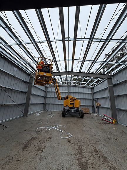 Interior view as crews add roof panels to structure using a lift crane.
