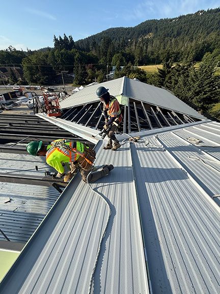 Metal roofing installation continues on sunny day in British Columbia.