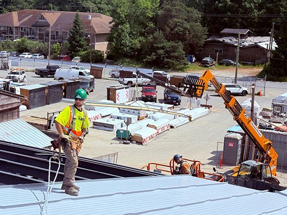 Construction worker standing on roof overlook Windsor Plywood project site.