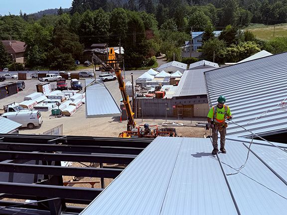 Skilled tradesperson walking along metal roof on BC construction site.