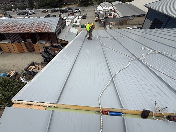 Securing metal roof panels on construction site.