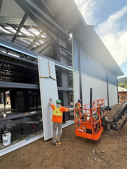 Double Black Construction crew continues to add metal wall system panels to Windsor Plywood building.