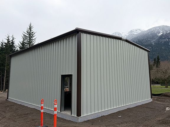 View of metal building project with white wall panels and brown trim.