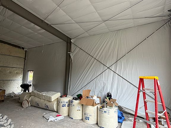 Interior of a large building under construction showing white insulated walls, structural cross-bracing and equipment.