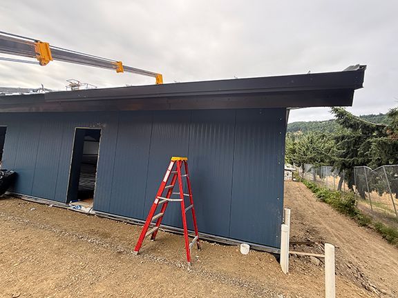 View of ladder next to metal building under construction.