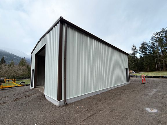 Brown trim complements the white metal wall panels of a pre-engineered steel building in Squamish.