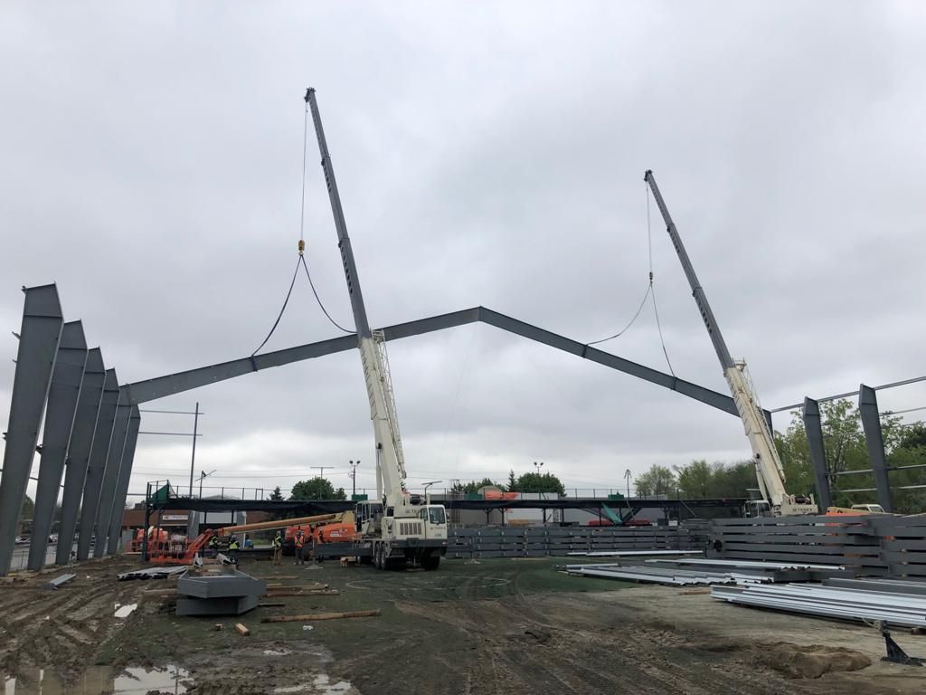 A crane is lifting a large metal structure in a construction site.