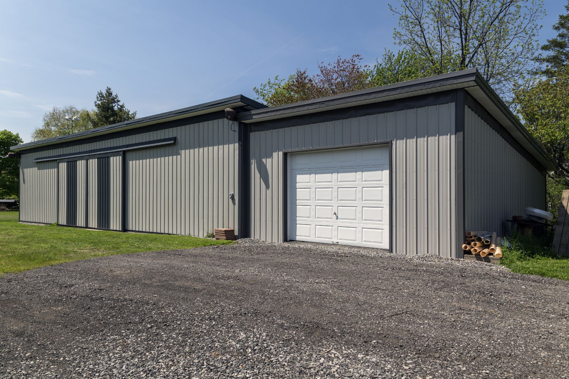 A large gray metal building with a white garage door