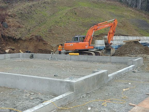 A large orange excavator is working on a construction site.