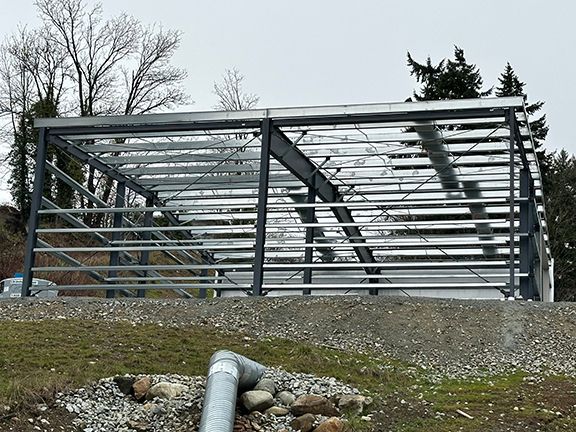 A metal structure is being built on top of a dirt hill.