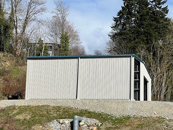 A white building with a blue roof is sitting on top of a dirt hill.