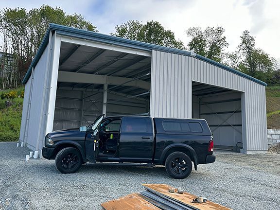 A black truck is parked in front of a metal building.