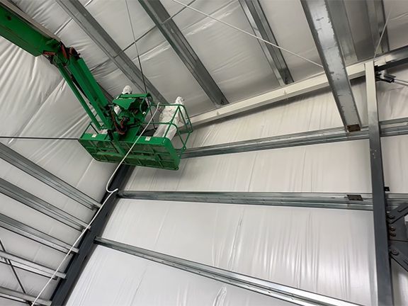 A green crane is sitting in the ceiling of a building.