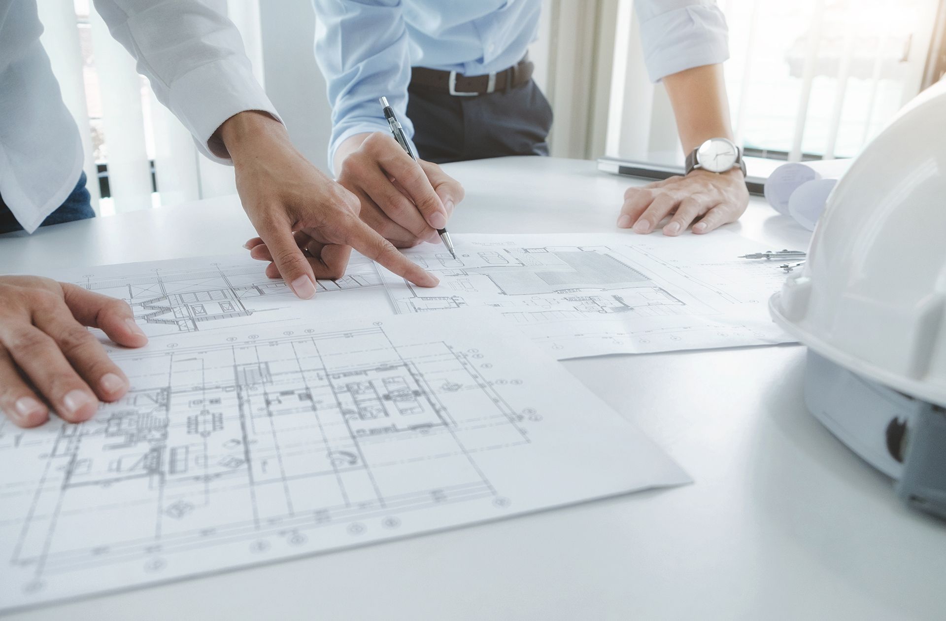 A group of people are sitting at a table looking at a blueprint.