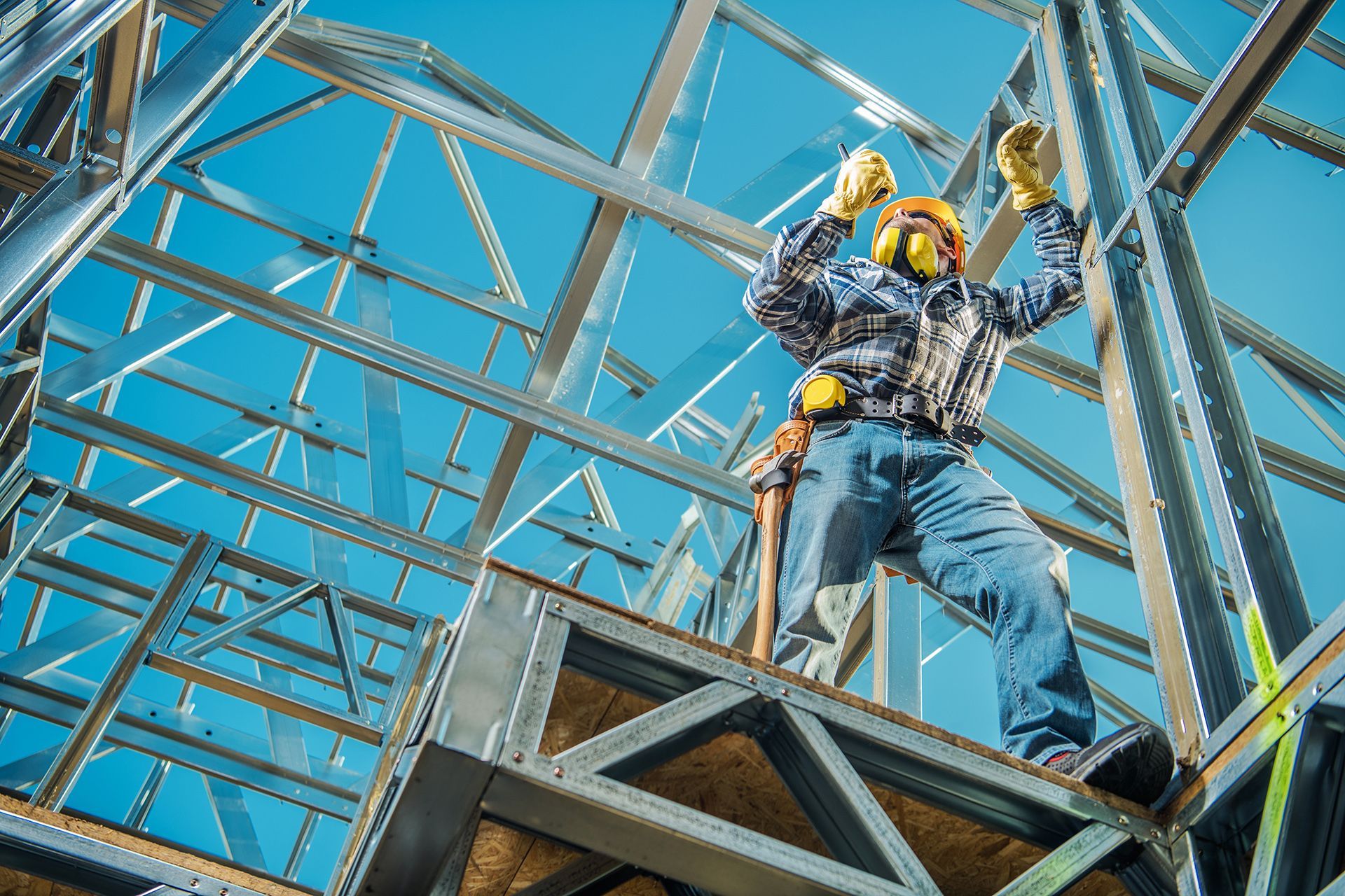 A construction worker is standing on top of a metal structure.
