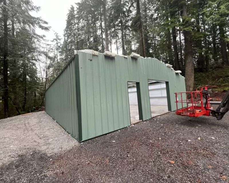 A green metal building with a red trailer attached to it