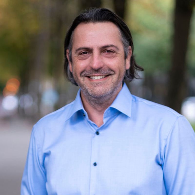 A man in a blue shirt is smiling for the camera.