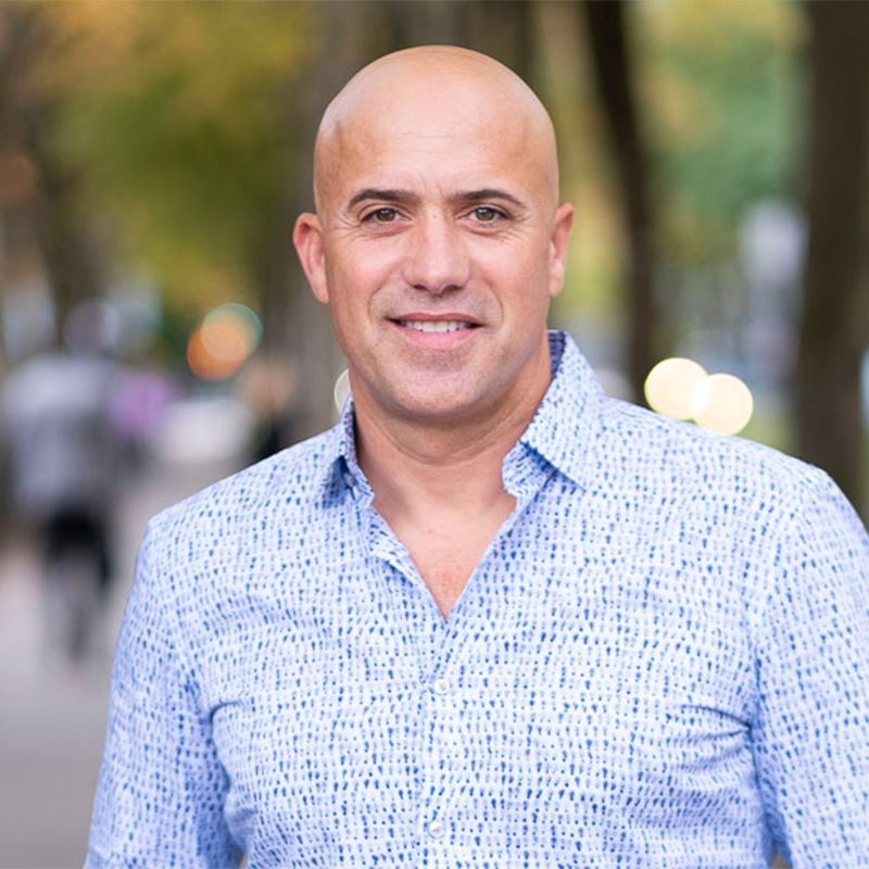 A bald man wearing a blue shirt is smiling for the camera.