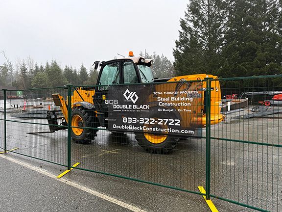 Double Black Construction banner in front of forklift and job site.