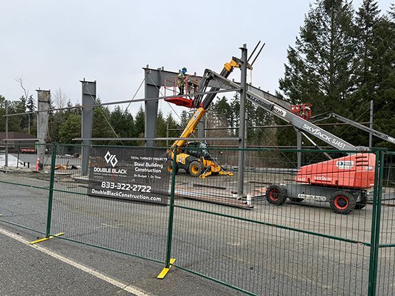 Skilled tradespeople add top sections to steel framing on construction site in BC.