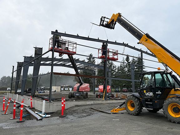 Skilled tradespeople adding metal framing for new industrial building in British Columbia.