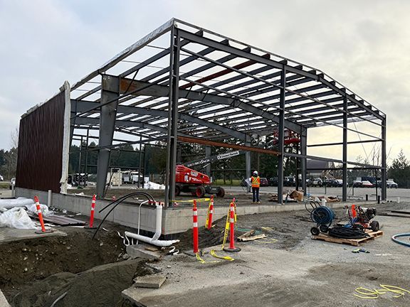 Engineer inspects jobsite and reviews blueprints at a metal building project in British Columbia.