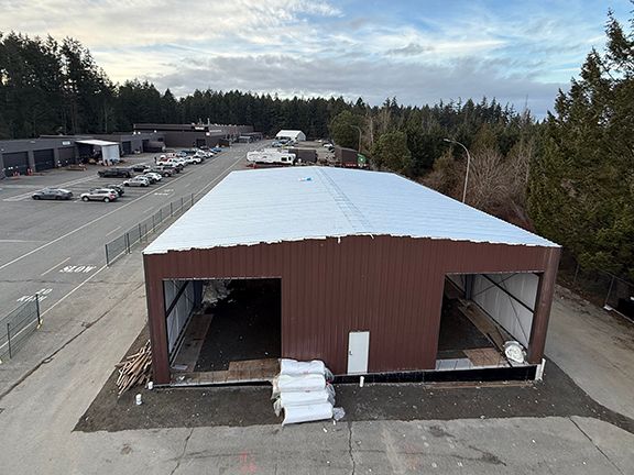 Construction site photo showing metal building and its completed roof.