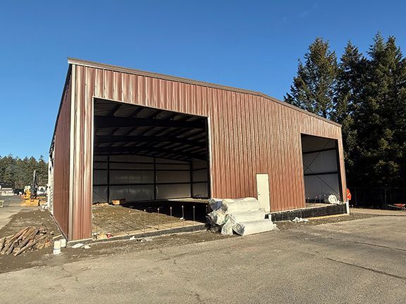 Brown metal building workshop photo with interior concrete floor waiting to be completed.