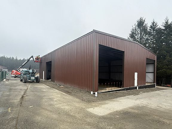 Nearly completed metal workshop building in British Columbia with crew adding final exterior panels.