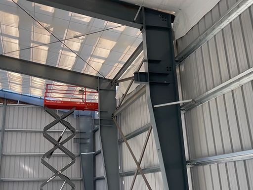 A person is standing on a scissor lift in a building.