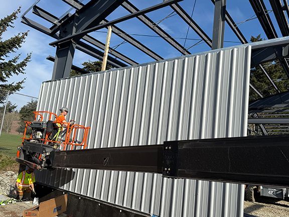 Grey metal siding being installed at a commercial building site in BC.