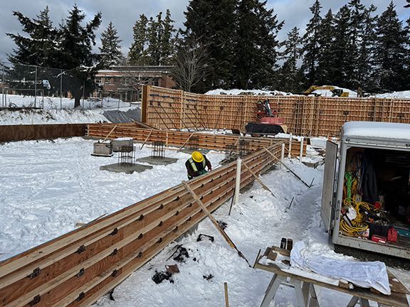 Construction team continues to add wooden forms that will shape and mould concrete walls.