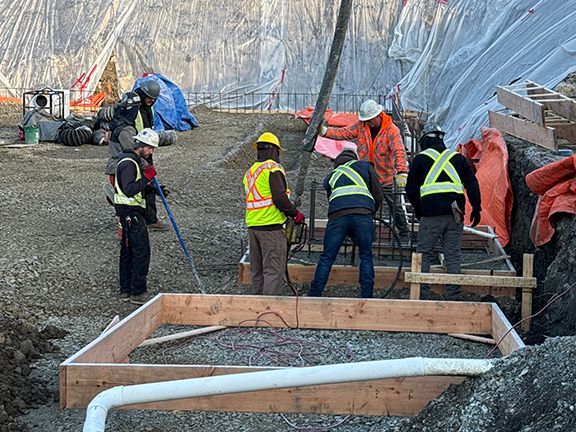 Crew of skilled tradespeople adding concrete to wooden form at jobsite on Salt Spring Island.