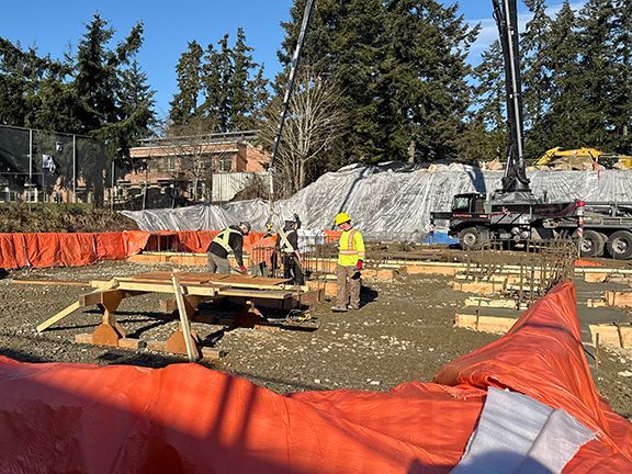 Teams preparing wood forms for future concrete work at Windsor Plywood construction site.