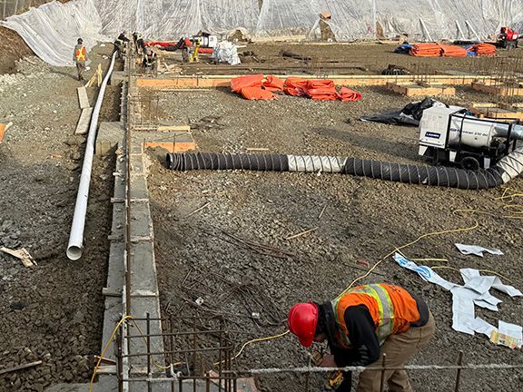 Skilled trades crew checking concrete and rebar foundation framing for future steel building.