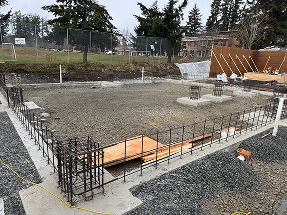 Perimeter of construction site with concrete foundation and rebar before steel frames have been installed.