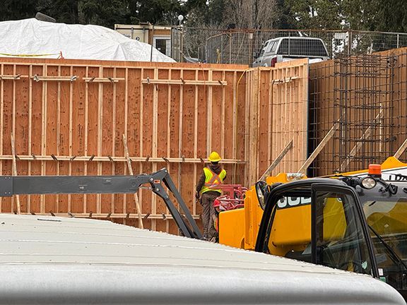 Construction worker inspects wood wall forms before concrete is poured.