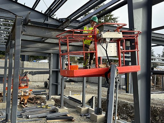Skilled tradesperson on a crane at a pre-engineered building construction site.