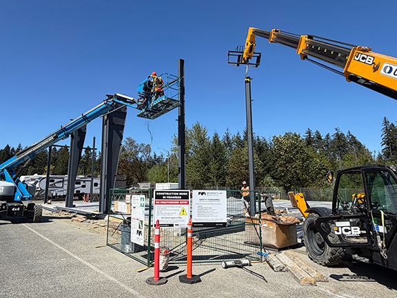 Skilled trades use crane to lower steel beams into place for PEMB project.