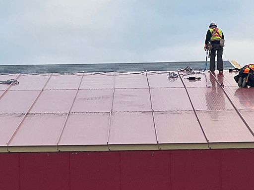 A man is standing on top of a red roof.