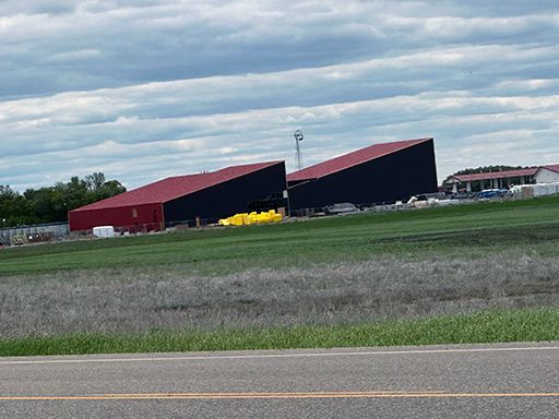 A large building is sitting on top of a grassy hill next to a road.