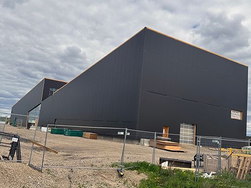 A large black building with a fence around it is under construction.