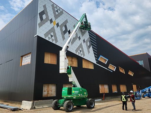 A man is standing in front of a building with a crane on it.