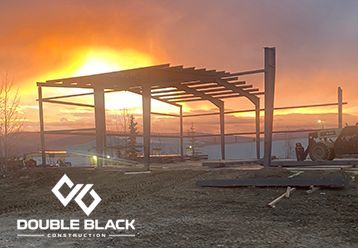 The sun is setting behind a building under construction.