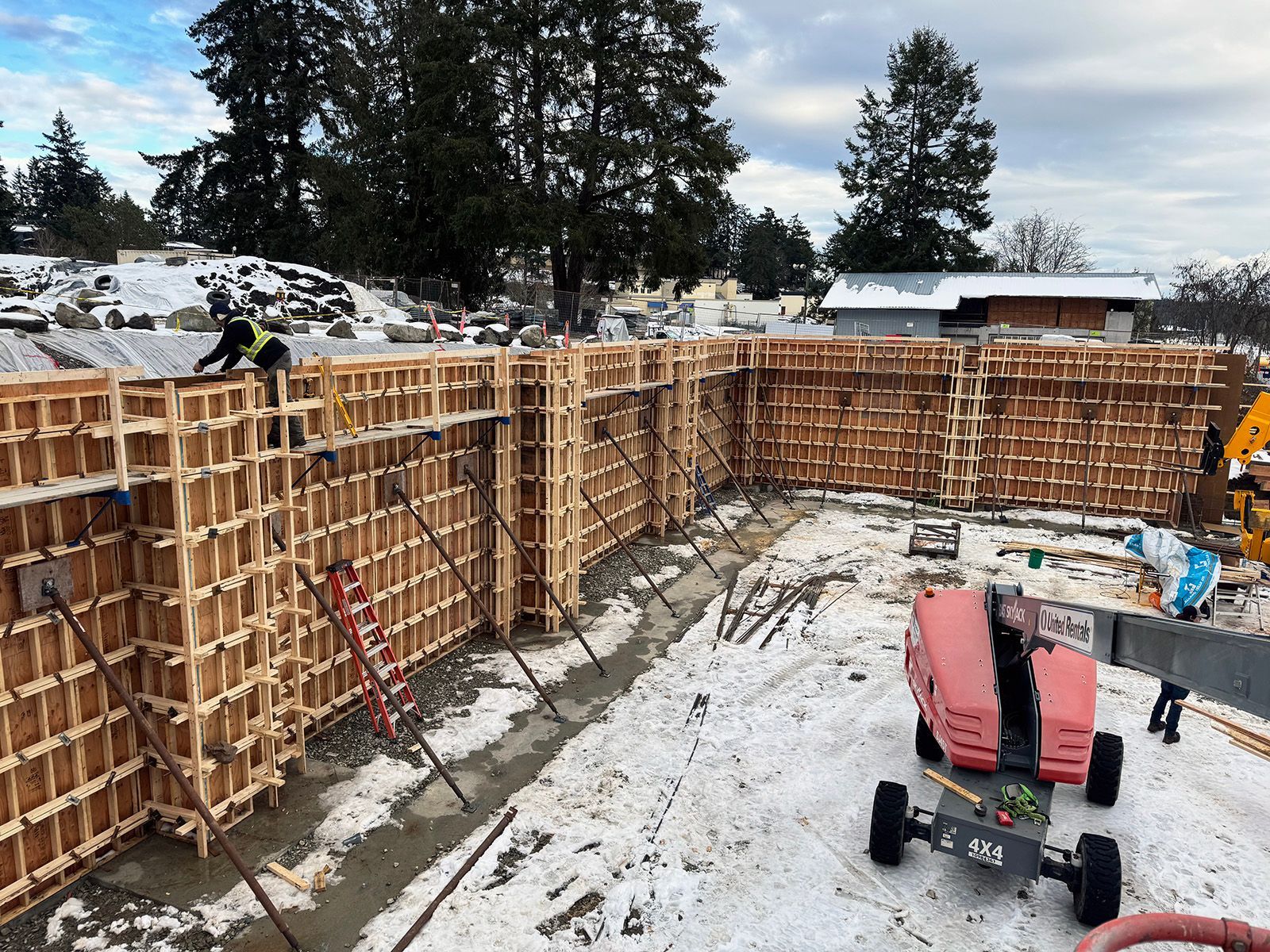 Construction site showing wood forms prepared for first phase of pouring concrete retaining wall.